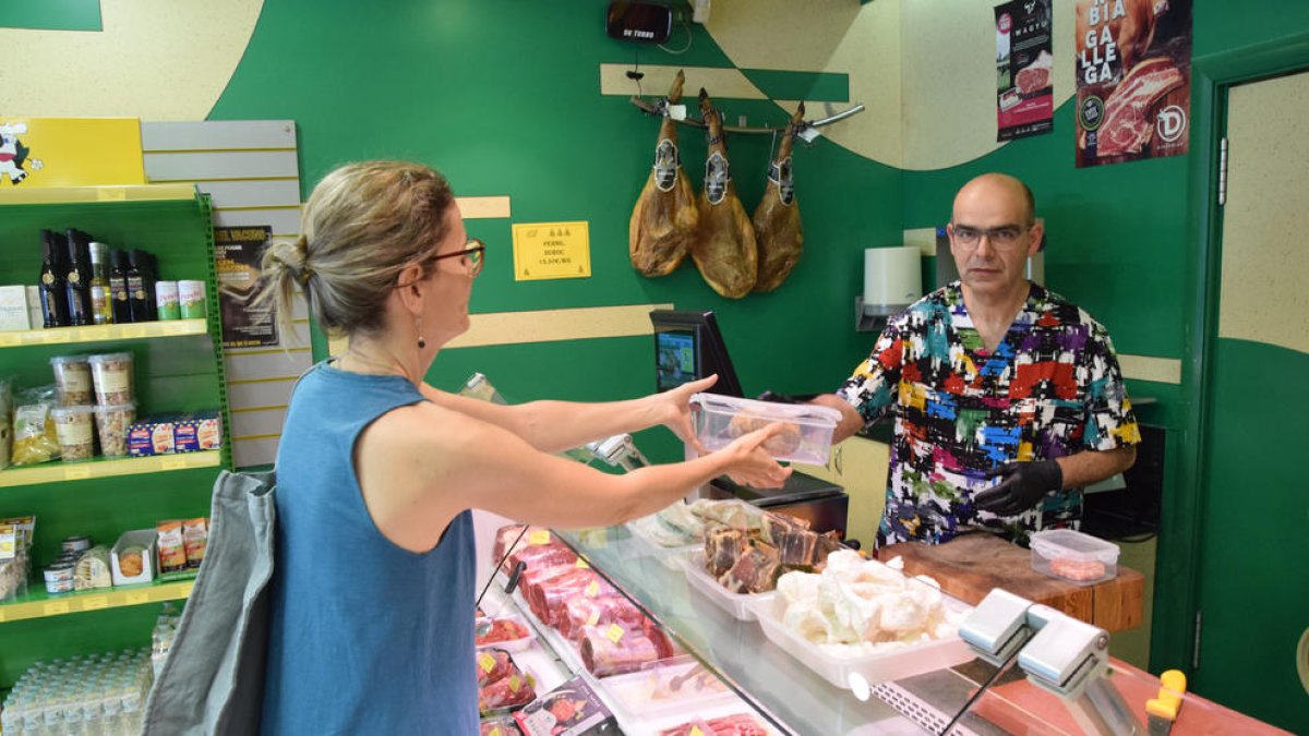 Compra de carne con ‘tuppers’ en un comercio de La Seu. 
