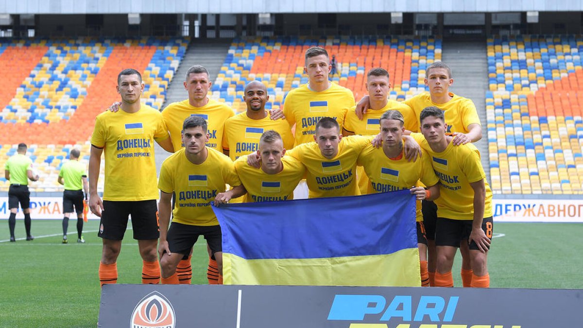 Els futbolistes del Xakhtar, amb una bandera ucraïnesa i un missatge en favor de la pau.