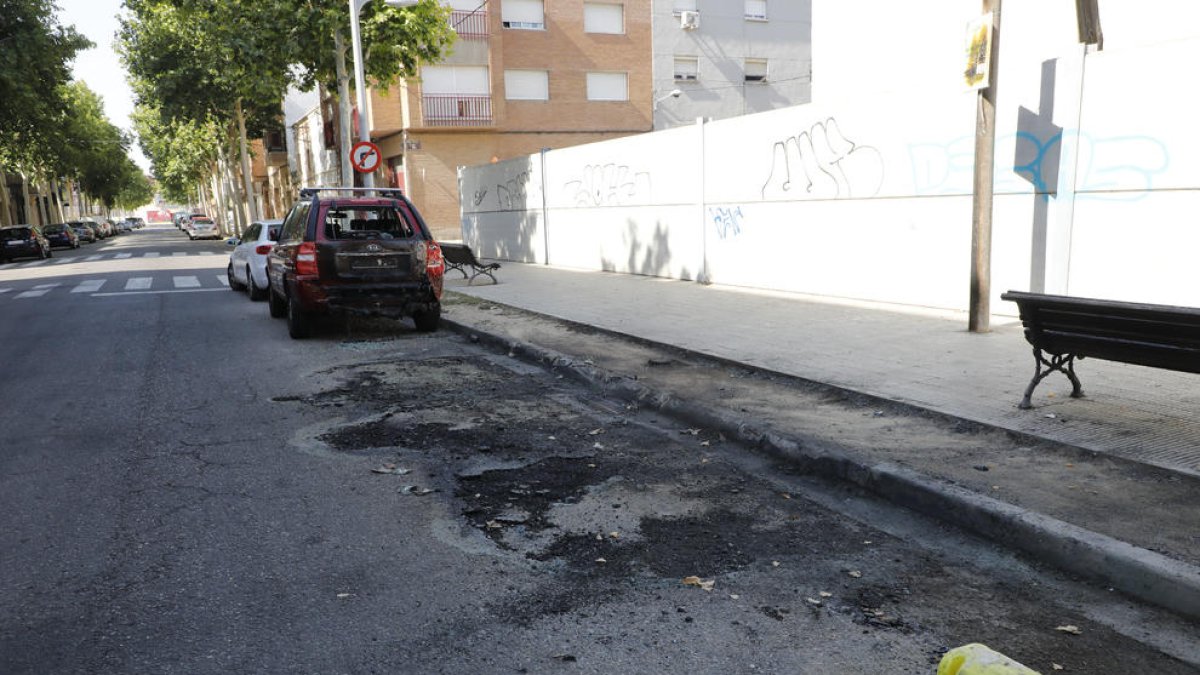 Restes de contenidors cremats, amb un vehicle afectat, diumenge a la Bordeta.