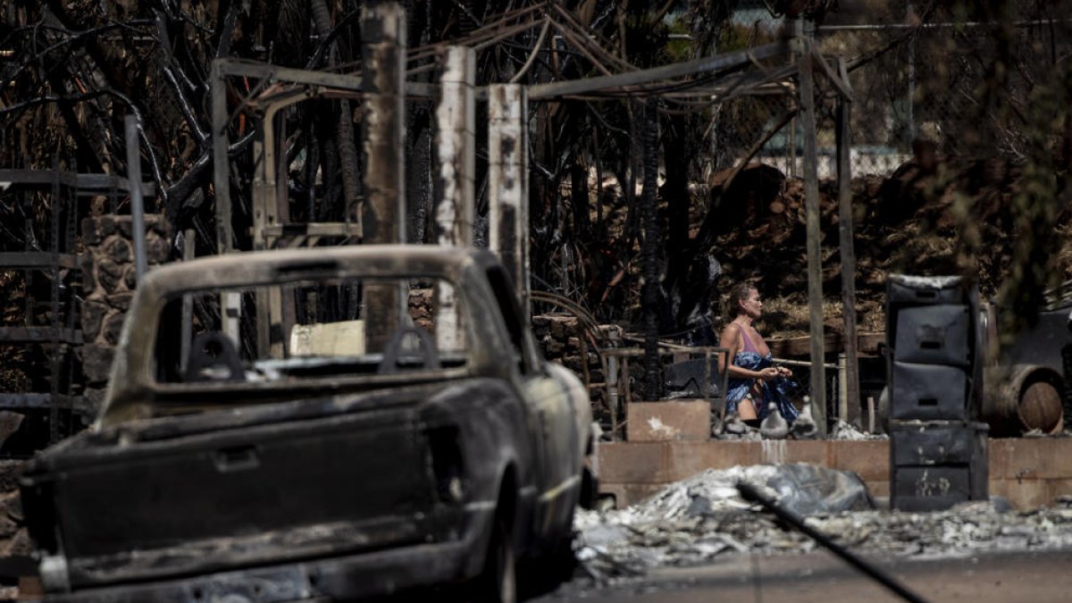 Una dona camina entre les ruïnes d’una casa destruïda per l’incendi a la localitat de Lahaina.