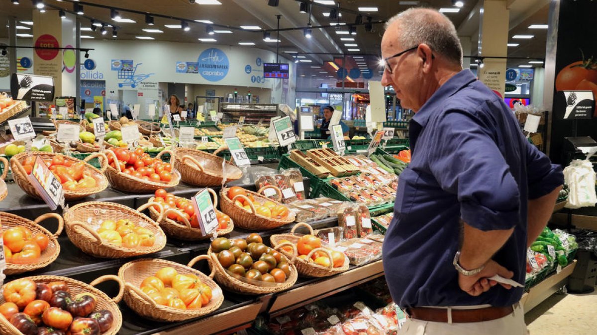 Un hombre compara los precios de la verdura en un supermercado.