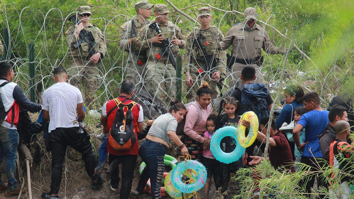 Militars observen migrants que travessen el riu Bravo per intentar entrar als Estats Units.