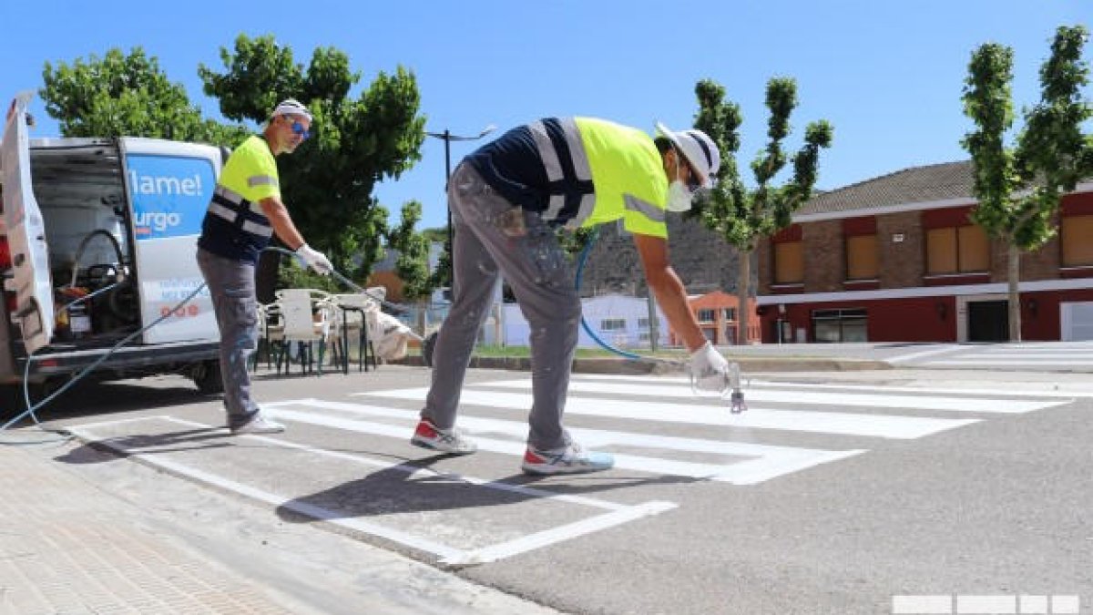 Operarios pintando uno de los pasos de cebra de Mequinensa.