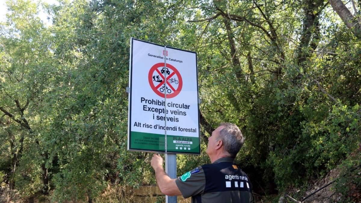 Un Agente Rural abre un cartel de prohibición del paso al Montsec en la zona de Corçà, en Àger, por la activación del plan Alfa 3.
