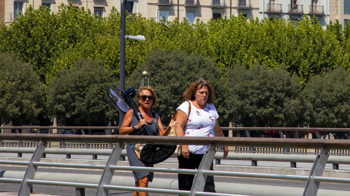 Una mujer cargando ayer un ventilador en Lleida ciudad. 