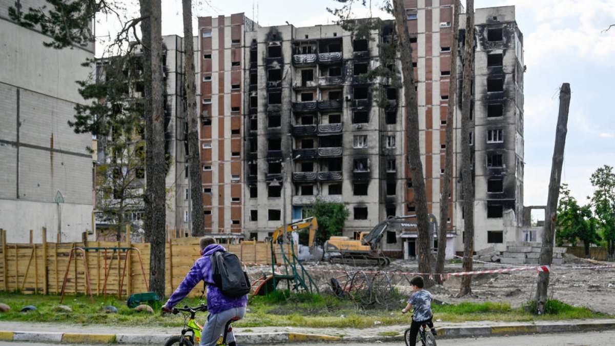 Un hombre y un niño junto a un edifico bombardeado en Ucrania.