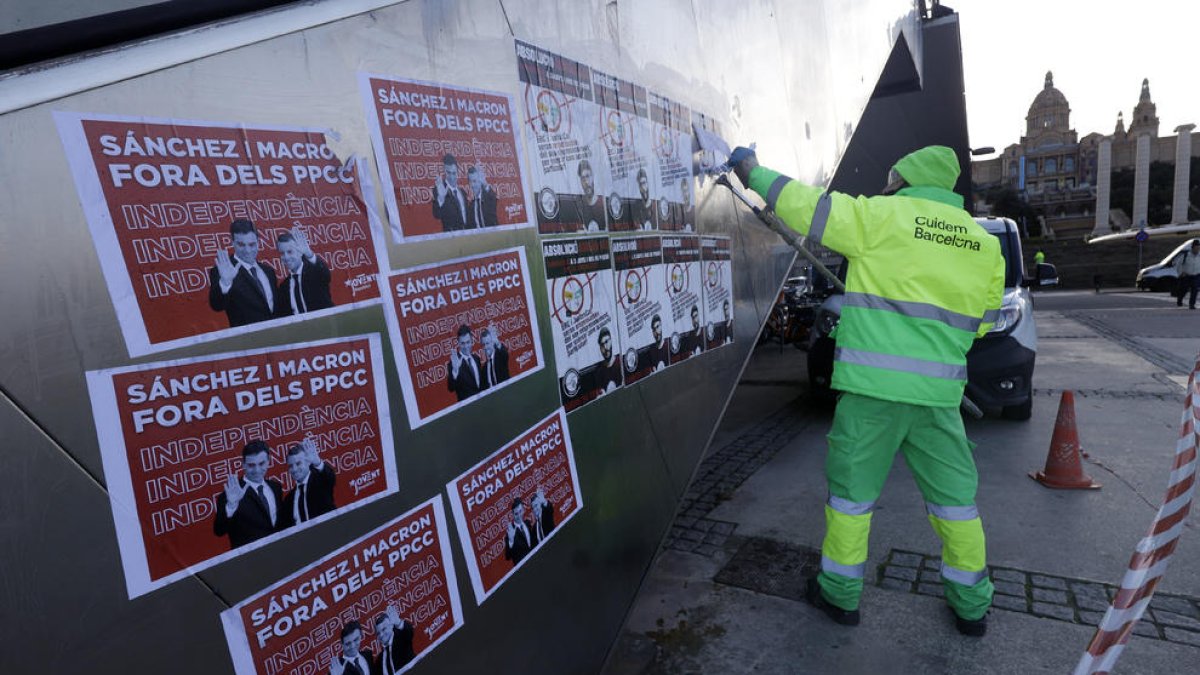 Personal de neteja eliminant pintades i retira cartells contra la cimera a Monjuïc.