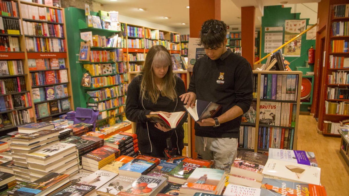 Dos jóvenes, esta semana en la librería Caselles de Lleida ante un expositor de novedades literarias.