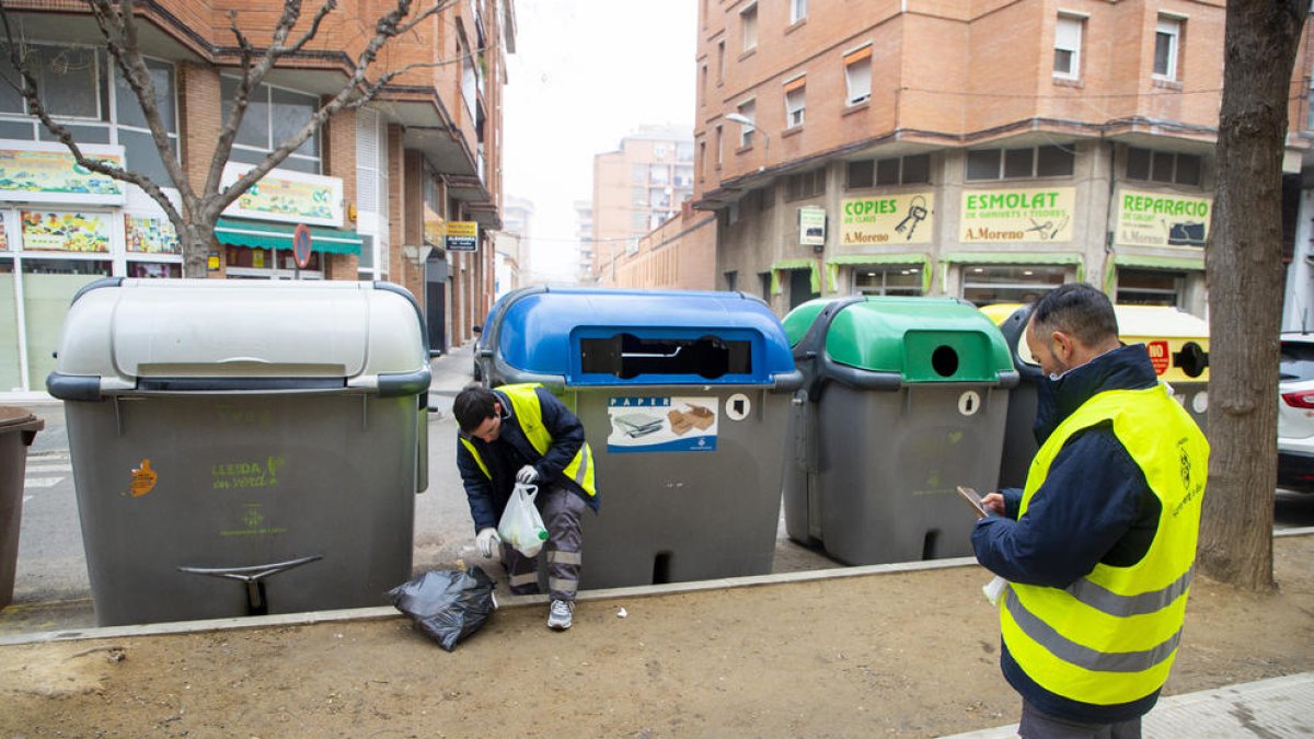 Un operario de la brigada recoge la basura de la calle mientras otro registra la incidencia o “punto negro” con el teléfono móvil. 