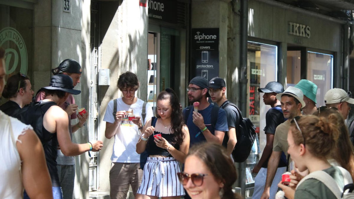 Un grup de joves menja un gelat per refrescar-se a la Rambla de Girona