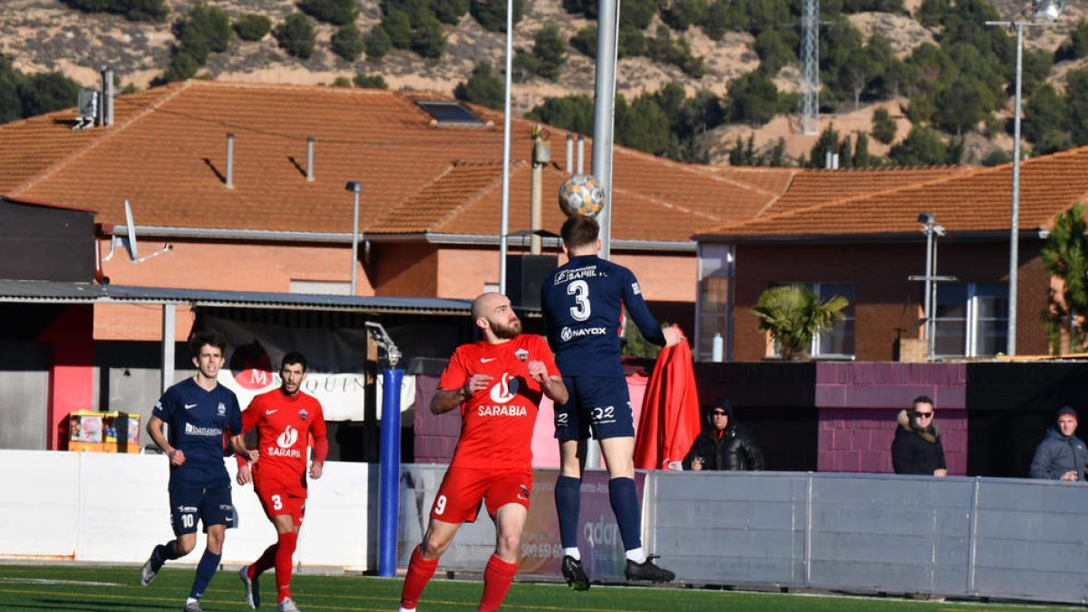 Domingo, de l’Atlètic Lleida, remata una pilota aèria amb l’oposició de l’atacant local Vendrell.