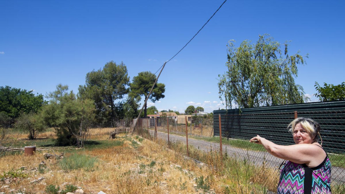 Mari Paz Choren mostra el cable de la llum trencat i que es recolza sobre la tanca.