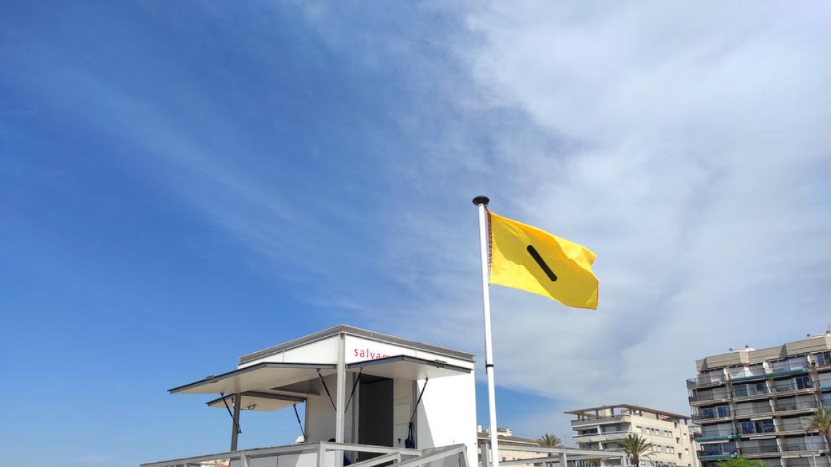 Una bandera adaptada al daltonismo señaliza el estado del mar en una playa de Calafell