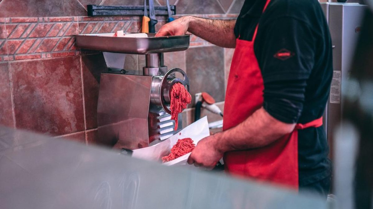 Un operari preparant  carn picada en una imatge d'arxiu.