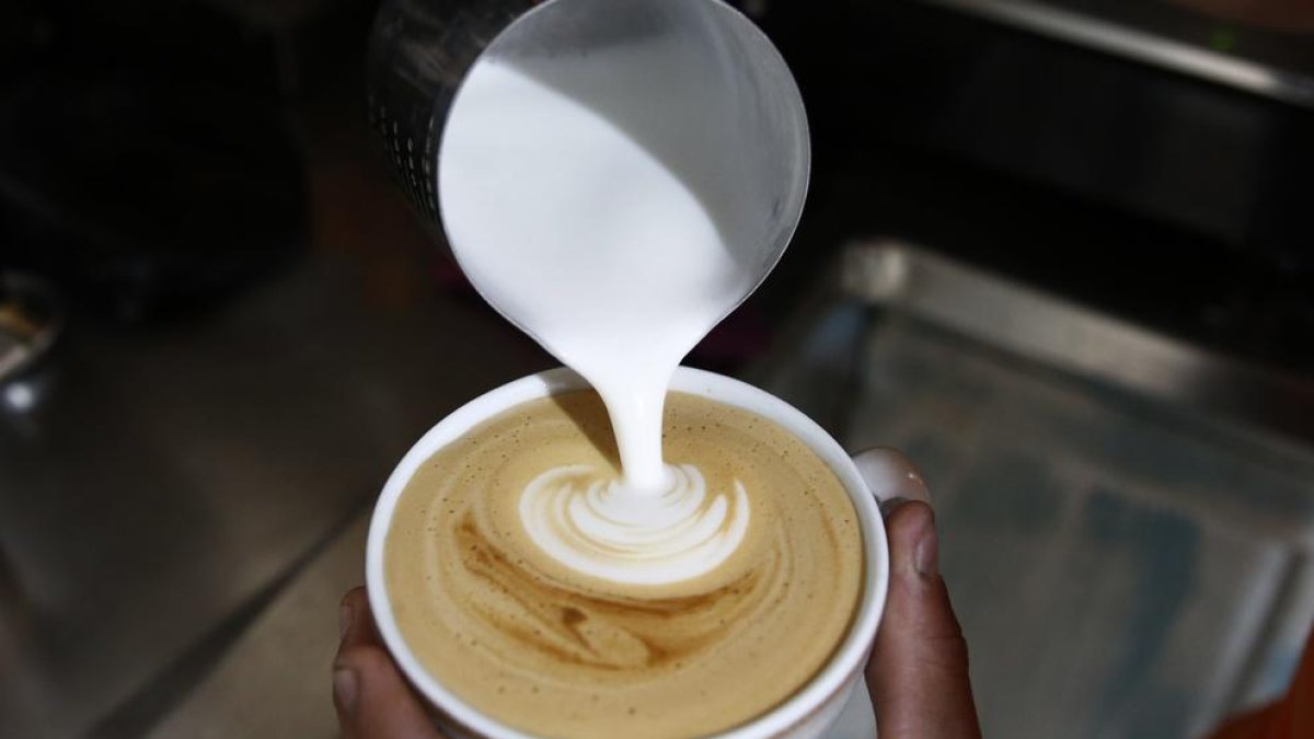 Fotografía de archivo de un hombre preparando una taza de café con leche.