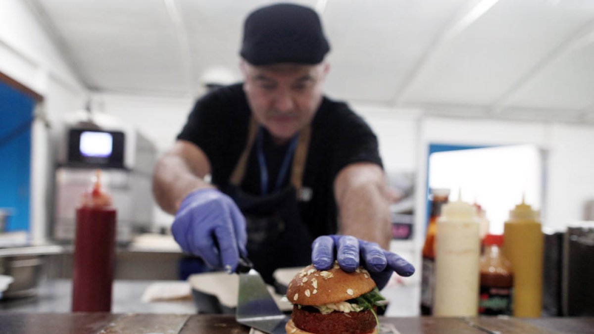 Un cocinero presenta una hamburguesa elaborada con proteína vegetal. 