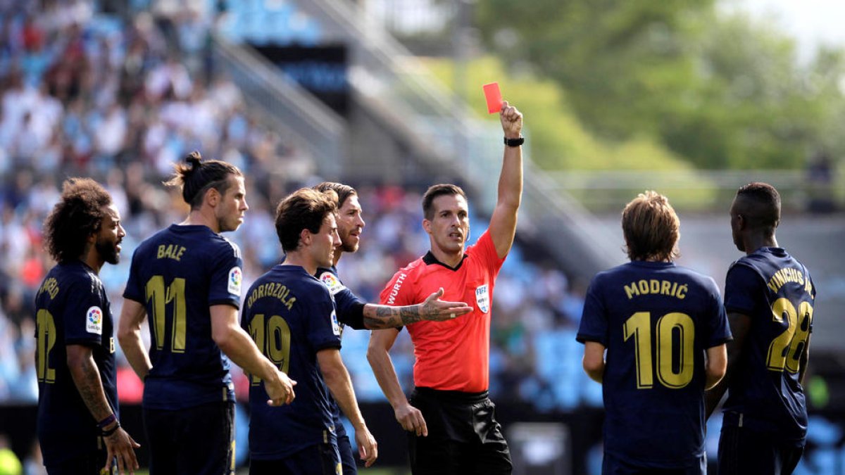 Xavier Estrada Fernández muestra una tarjeta roja a un jugador del Real Madrid.