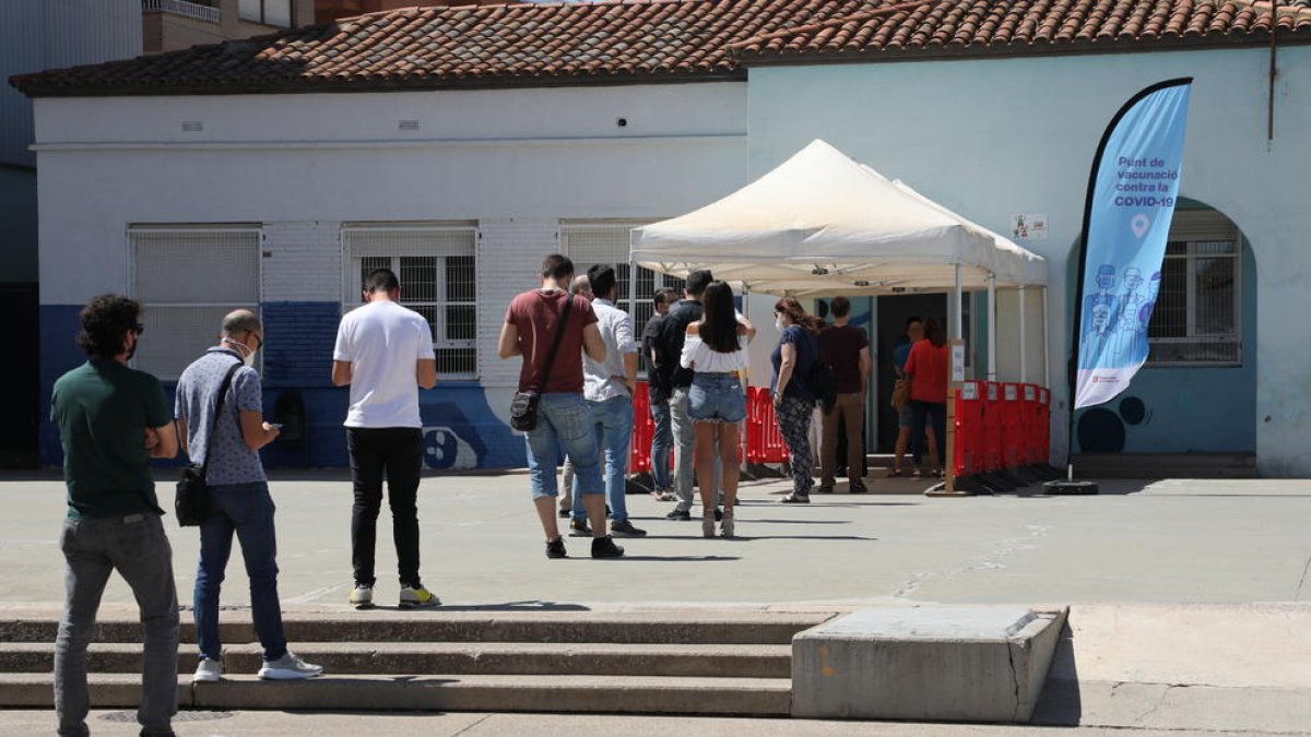 Diverses persones fent cua ahir a la tarda al punt de vacunació contra la Covid a Alcarràs.