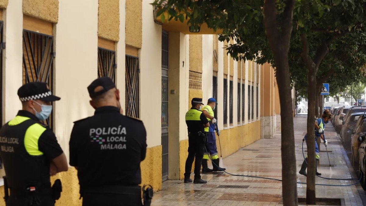 Dos operarios limpian la puerta del colegio de Málaga frente a la cual  se cometió el crimen.