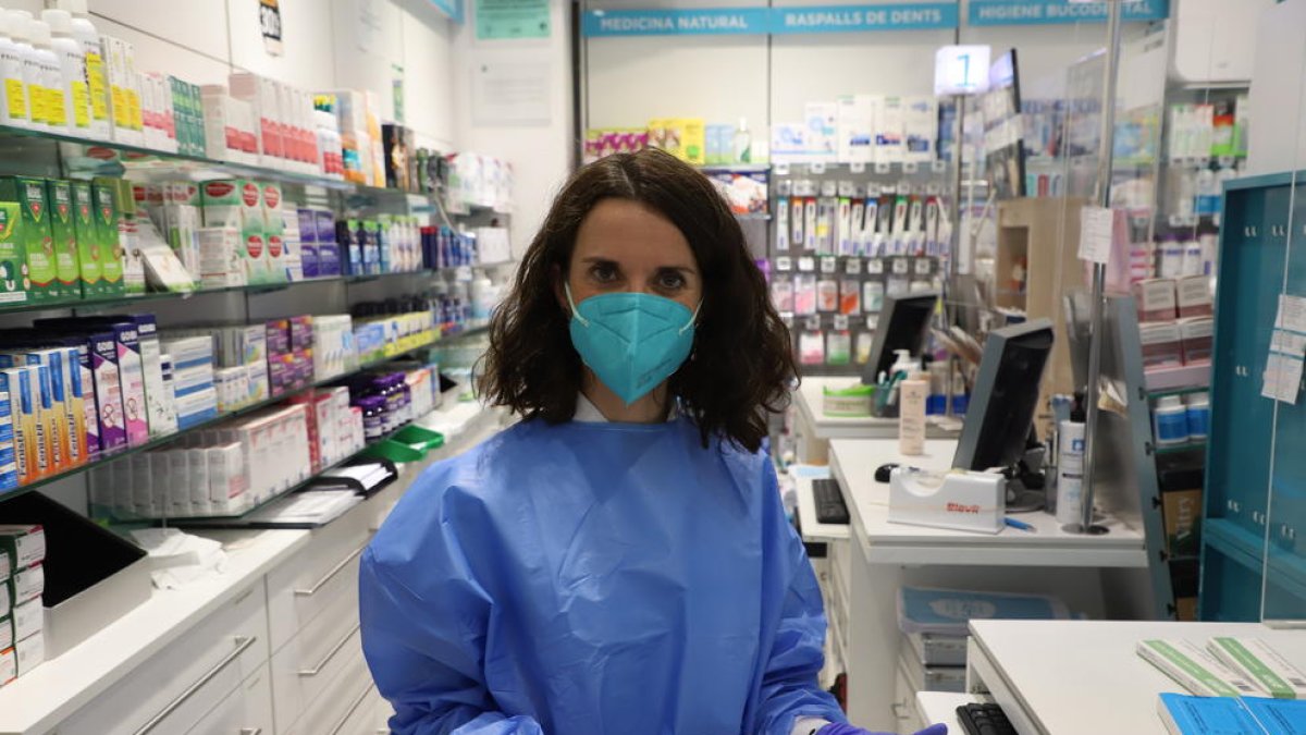 Una empleada de la Farmàcia Garrós de Lleida mostra els tests d’antígens en venda.