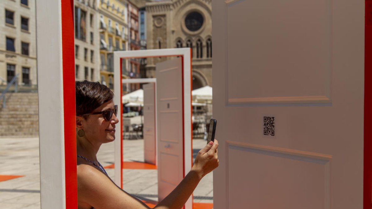 Una mujer fotografía el código QR de una de las puertas de la instalación ubicada en la plaza Sant Joan.
