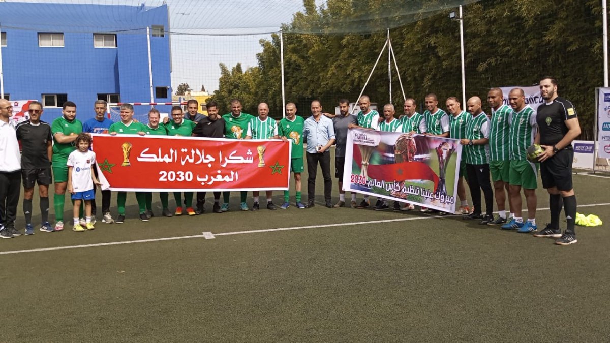 L’equip de Lleida i el de veterans del KAC de Kenitra posen abans d’un partit amb la pancarta recordant el Mundial 2030.