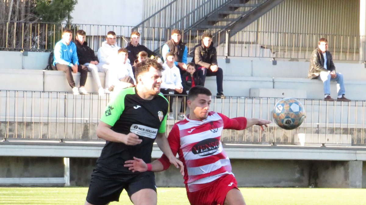 Un futbolista de l’Almacelles forceja amb un rival per intentar emportar-se la pilota.