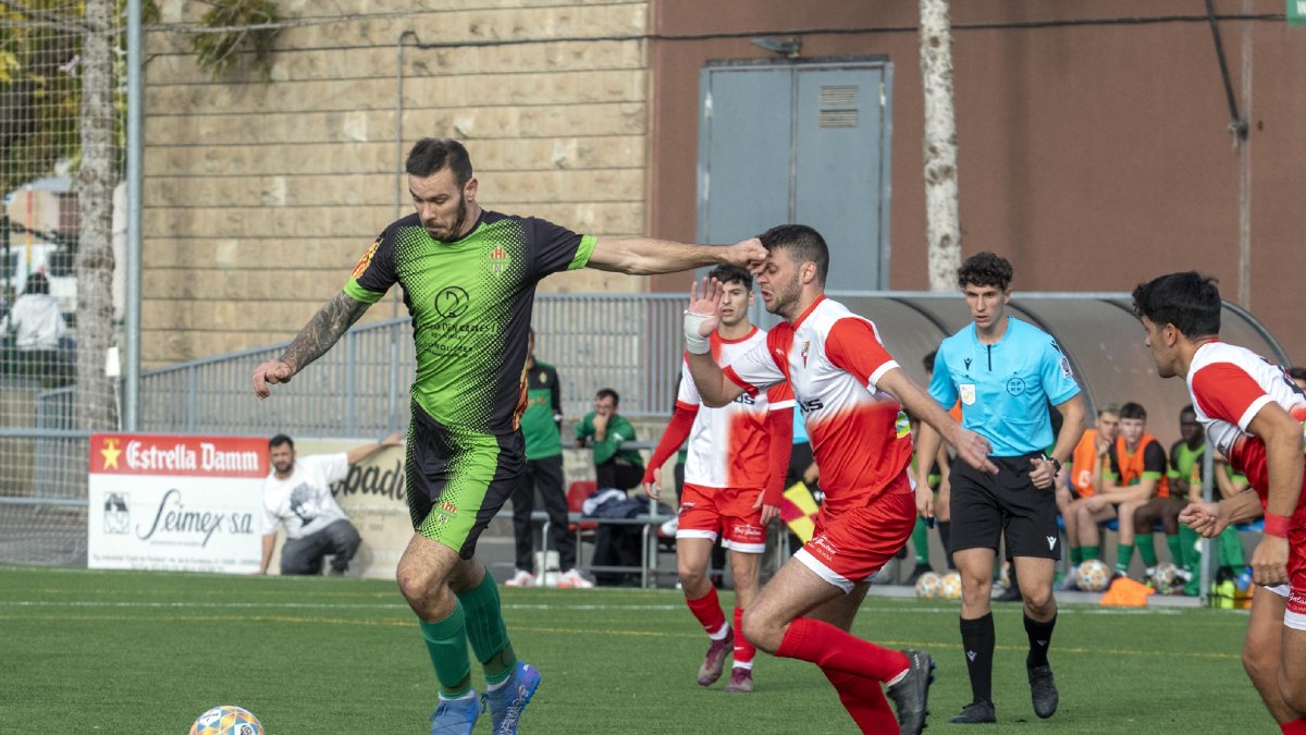 Un jugador del Cervera es disposa a rematar davant l’oposició d’un rival, a qui pica a la cara.