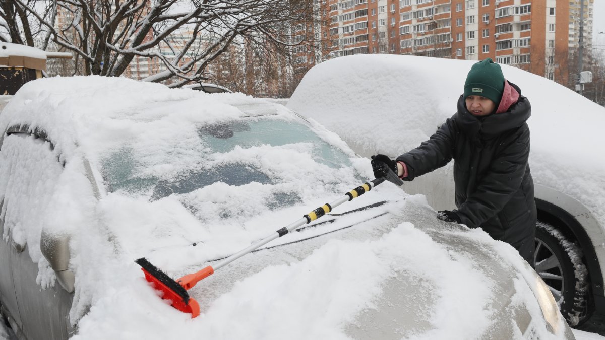 Una dona treu la neu acumulada al seu cotxe.