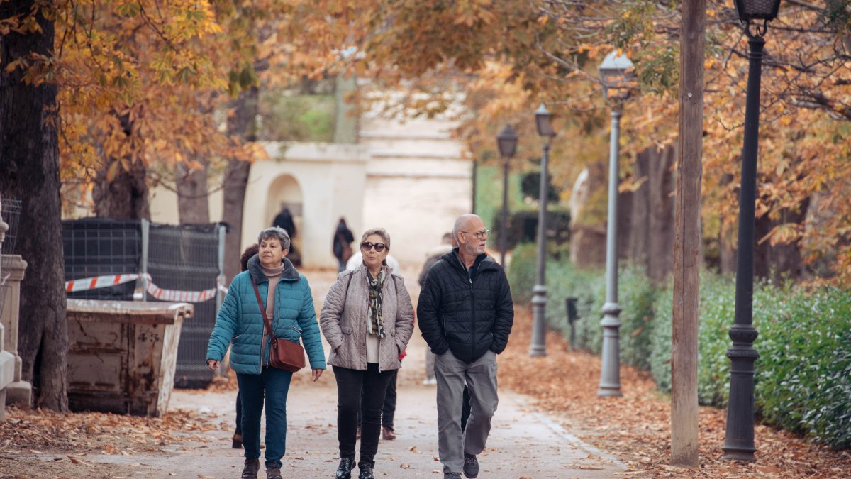 Unes persones en edat de jubilació passegen per un parc en una típica imatge tardoral.