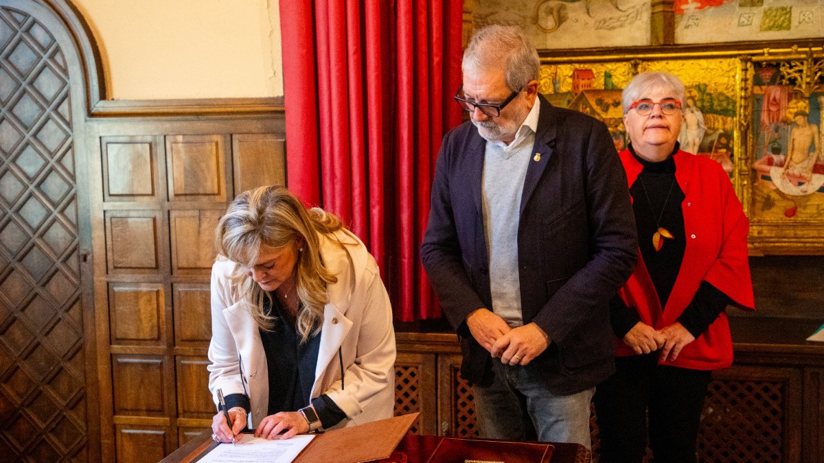 La portaveu de Junts, Violant Cervera, firmant l’acord davant de la mirada de l’alcalde, Fèlix Larrosa.