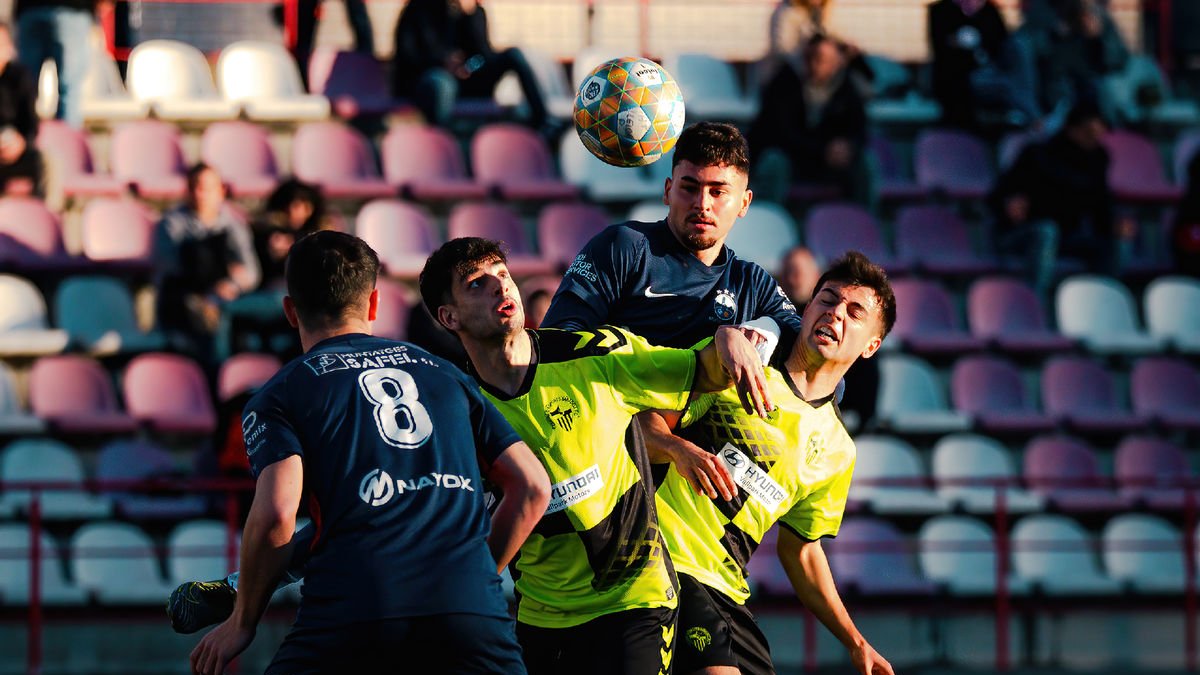 Àngel i Bayu, de l’Atlètic Lleida, pugnen per una pilota amb dos rivals.