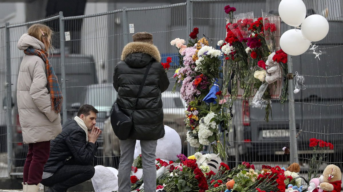 Una família russa deixa flors en un memorial als morts en l’atemptat a la capital de Rússia.