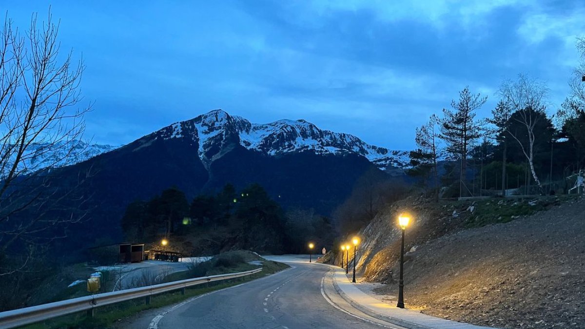 La vorera il·luminada de nit i els contenidors d’escombraries al fons.