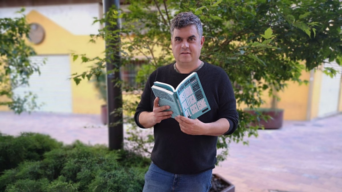 Ramon Usall sosté dos exemplars del seu últim llibre en les edicions en català i castellà.