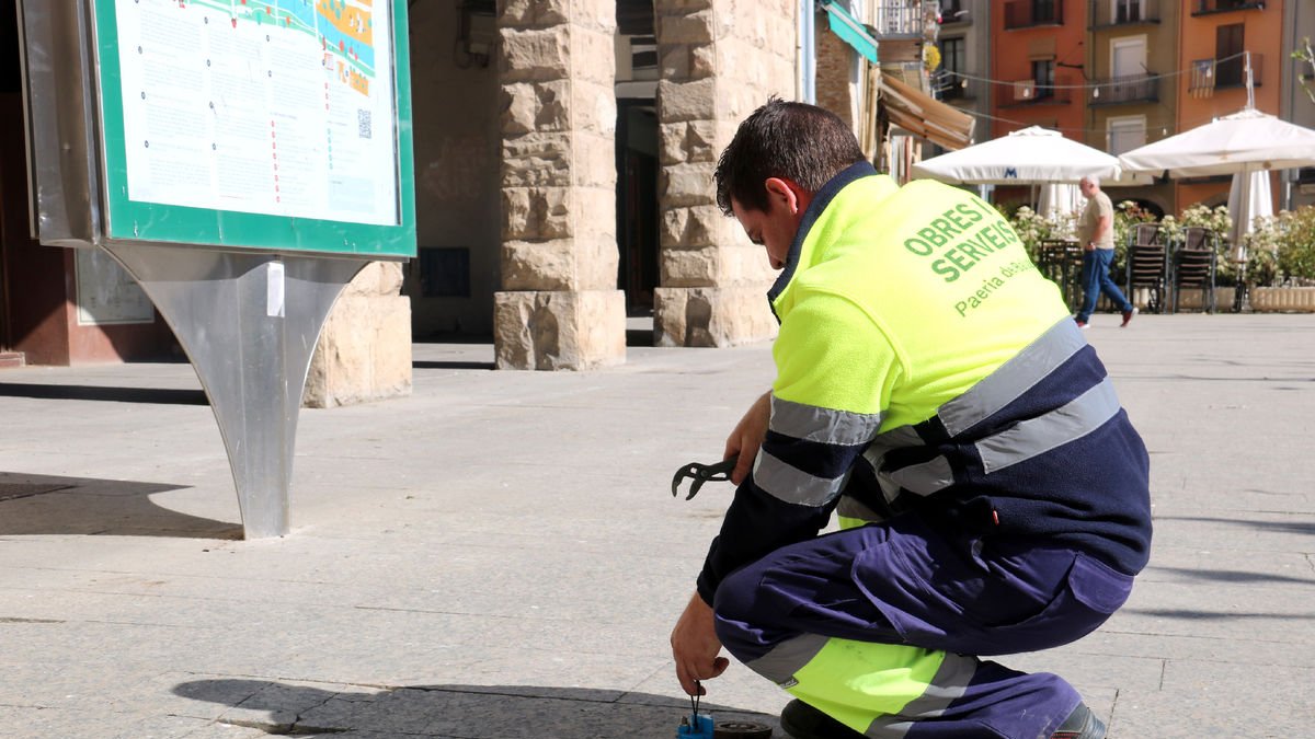 Un treballador municipal de Balaguer instal·la un sensor detector de pèrdues d’aigua.
