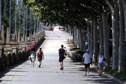 Peatones caminando por la sombra en Lleida bajo un intenso calor.