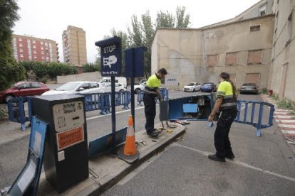 Operaris retirant les màquines i les barreres del pàrquing de Magisteri, des d’avui fora de servei.