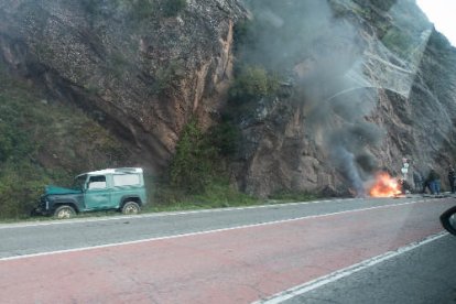 Imatge del totterreny i, al fons, la moto cremant i ciutadans atenent el motorista.