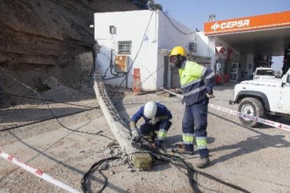 Dos operaris, davant de la torre elèctrica abatuda per una roca a l’estació de servei de la Portella.