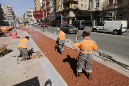 Tres operaris treballaven ahir en la col·locació del paviment del carril per a bicicletes.