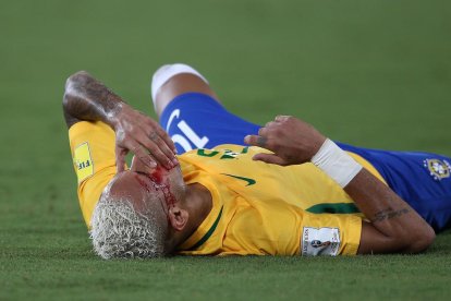 Neymar, ajagut a la gespa amb la cara ensagnada després del cop de colze que li va clavar un rival.