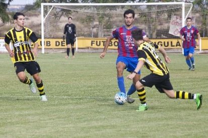 Un jugador del Torà controla l’esfèrica davant la pressió de dos jugadors de l’Angulària.