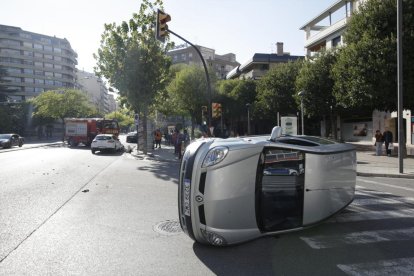 En primer pla el vehicle bolcat i, al fons, el turisme implicat en el sinistre.