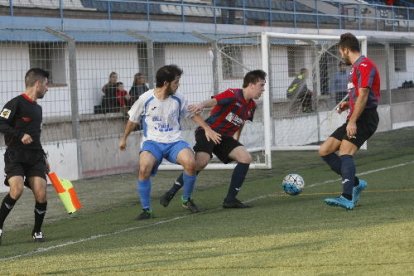 Un jugador del Mollerussa pugna amb dos rivals per obtenir el control de la pilota a prop de la banda en una acció del partit.