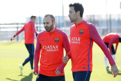 Iniesta, que reapareixerà avui després de la lesió, conversa amb Busquets.