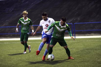 Un jugador visitante protege el balón ante la presión de un jugador del Binéfar.