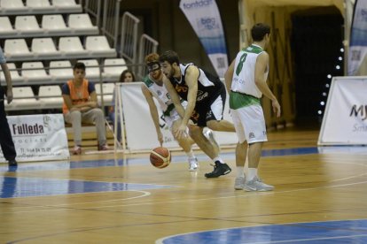 Sevillano se lleva el balón perseguido por un rival.