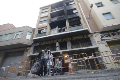 Momento en el que varios vecinos abandonaban el edificio acompañados por los bomberos. 