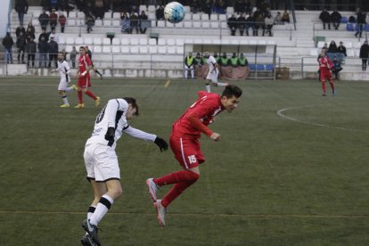 Dos oponentes pugnan por un balón aéreo en un lance del partido.